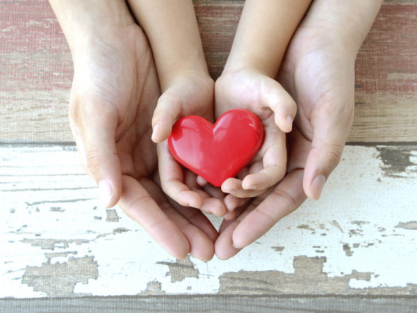 Red heart in child and mother's hands
