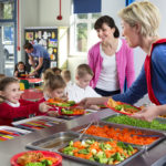 Dinner is served out to children as they line up at a school canteen