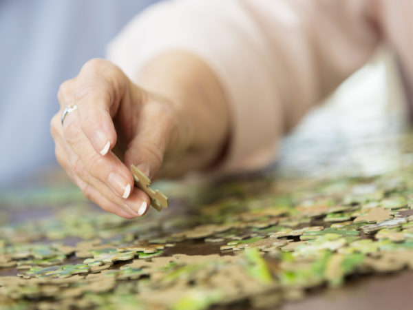 Close up of senior woman's hand putting together puzzle