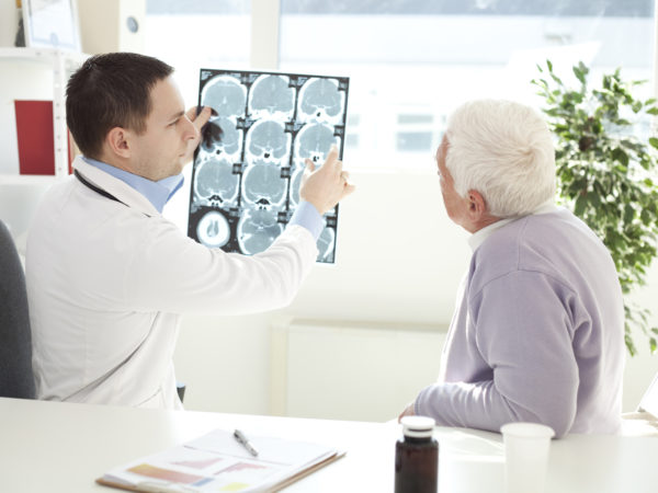 Senior man at doctor's office. Doctor analyzing a CT scan of head