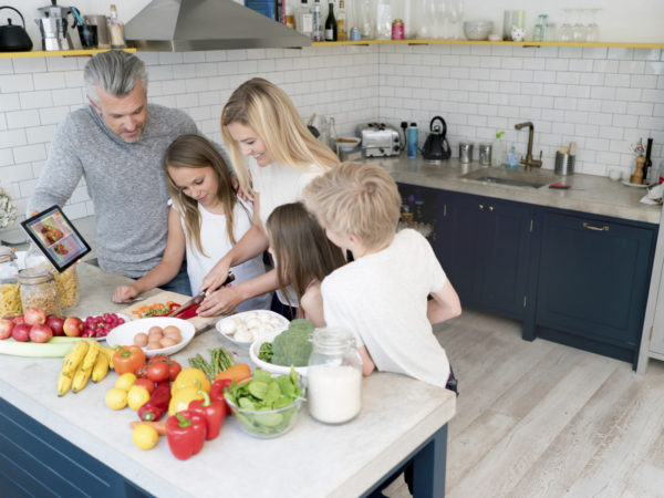 Family cooking dinner together at home and looking very happy. Design on tablet is own design.